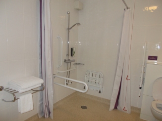 Wet room- Shower is open wet room style. Towel rack with neatly folded towels on top.